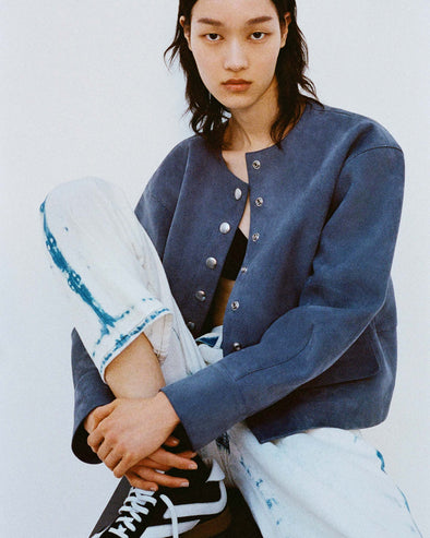 Cropped image of model sitting down against a white backdrop in the Robin Jacket in Suede in Slate