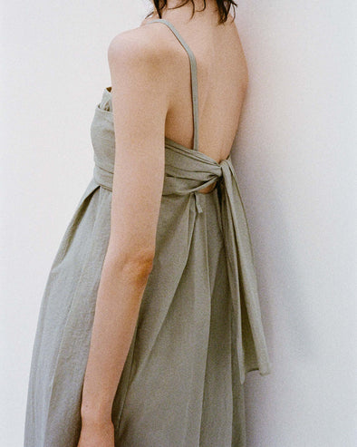 Cropped image of model's side standing against a white backdrop wearing the Claudine Dress in Tech Poplin in Sage
