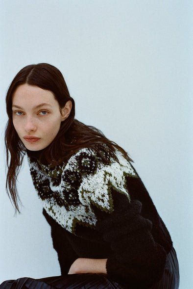 Image of model wearing Lizzy Sweater in Textured Fairisle in Black multi against a light blue background