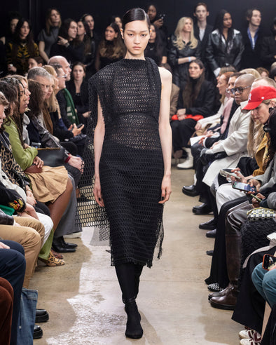 Model Walking in Proenza Schouler Fall Winter 2024 Runway Show Wearing Maude Dress in Black Technical Lace and Tee Over the Knee Boots in Black Viscose Knit