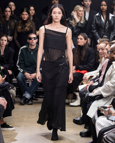 Model Walking in Proenza Schouler Fall Winter 2024 Runway Show Wearing Dani Dress in Black Crepe Chiffon / Wool Gabardine and Tee Over the Knee Boots in Black Viscose Knit