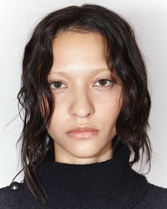 portrait of model America Gonzalez wearing a textured black knit sweater against a white backdrop