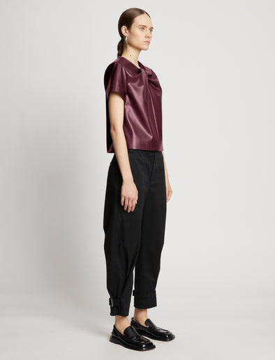 Side full length image of model wearing Faux Leather Twisted Top in PLUM