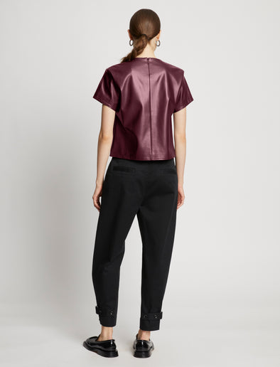 Back full length image of model wearing Faux Leather Twisted Top in PLUM