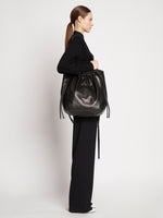 Side image of model carrying Drawstring Tote in BLACK