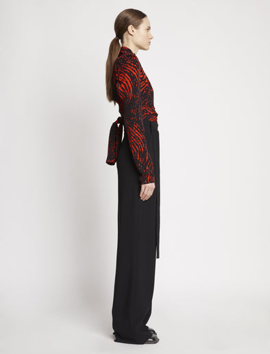 Side full length image of model wearing Painted Spiral Crepe De Chine V-Neck Top in RED MULTI