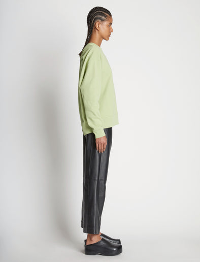 Side full length image of model wearing Long Sleeve Sweatshirt in GREEN TEA