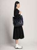 Side image of model carrying Drawstring Tote in DARK NAVY