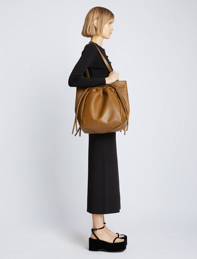 Image of model carrying Drawstring Tote in BARK on shoulder