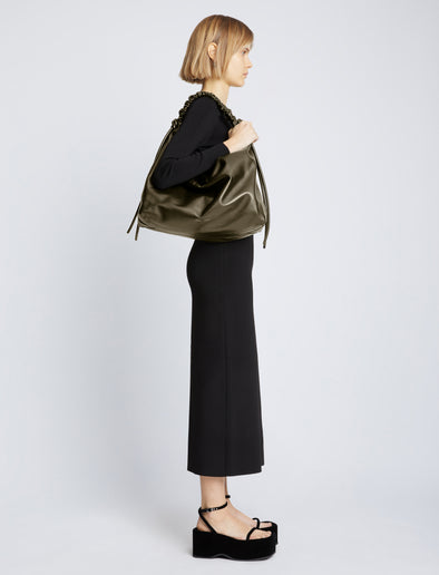 Image of model carrying Large Drawstring Shoulder Bag in OLIVE on shoulder