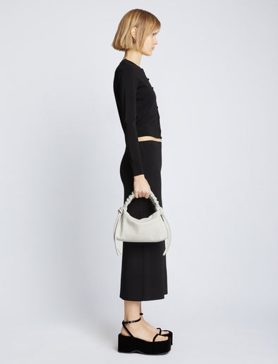 Image of model carrying Mini Drawstring Bag in OPTIC WHITE