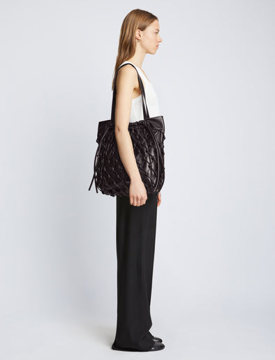 Image of model carrying Macrame Drawstring Tote in BLACK on shoulder