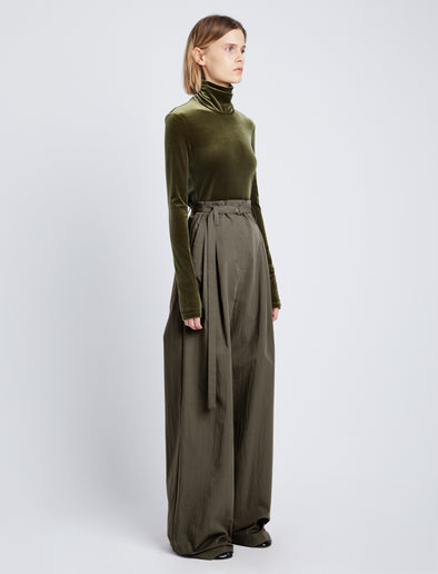 Side full length image of model wearing Stretch Velvet Turtleneck Top in MILITARY