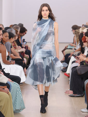 Model Walking Proenza Schouler SS24 Runway In Zoe Dress In Slate Printed Nylon Jersey, Flip Shoulder Bag In Gold Metallic Lacquered Nylon, Bronco Oxfords In Black Perforated Calf