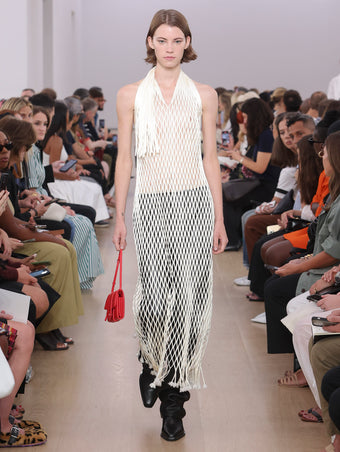 Model Walking Proenza Schouler SS24 Runway In Zora Dress In Ivory Satin Ribbon, Roy Jean In Black Nappa, Flip Shoulder Bag In Red Nappa Leather, Bronco Chelsea Boots In Black Shiny Calf