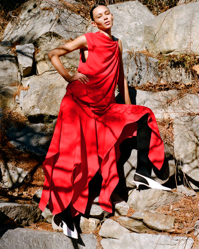 Image of model wearing Denise Dress in Light Matte Double Crepe in Red standing on rocky terrain