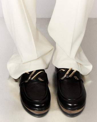 Cropped image of model wearing Monogram Loafers in black with white pants