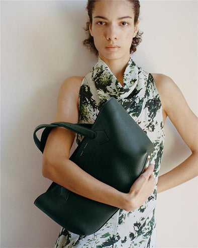 Proenza Schouler Front full length image of model wearing Adelide Dress in Printed Silk Viscose in Dark Green Multi holding the East West Chelsea Tote in Pebbled Calf Bottle.