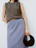 Cropped image of a model leaning against a white backdrop, wearing Bradley Crewneck in Plaid Knit in Off White/Black and Lori Knit Skirt in Plaid Knit Off White/Denim