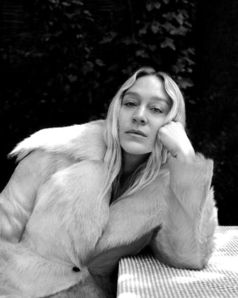 4x5 black and white image of Chloe Sevigny sitting outdoors leaning on a picnic table with gingham table cloth 