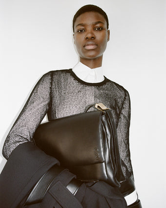 4x5 Cropped image of a model Elvina Patrick holding City Messenger Bag in black.