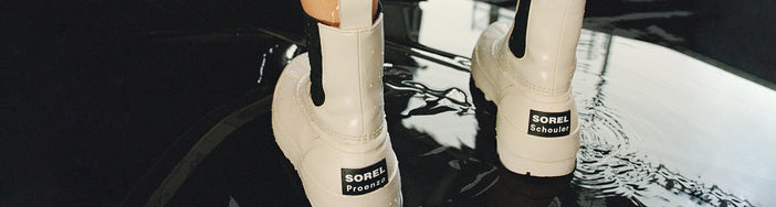 Image of model standing in puddle wearing SOREL x Proenza Schouler Caribou Chelsea Boots in chalk black