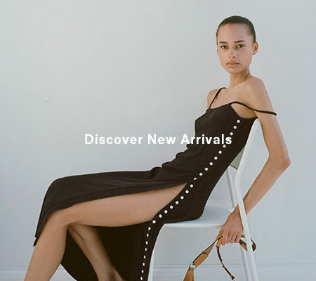 Image of model sitting in chair wearing Astrid Knit Dress in Boucle Viscose in black, 'Discover New Arrivals' overlaid