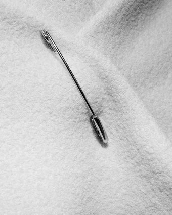 black and white close cropped image of a silver safety pin in fabric 