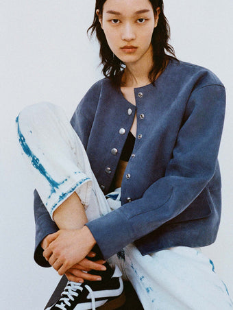 Cropped image of model sitting down against a white backdrop in the Robin Jacket in Suede in Slate