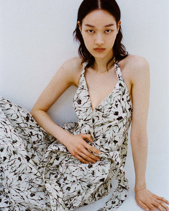 Cropped image of model sitting against white backdrop wearing the Rhea Dress in Printed Poplin in Light Butter/Black.