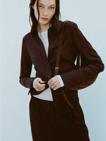 Image of model wearing Maddi Shirt in Merino Wool Twill in Chocolate over a white shirt against a light blue background