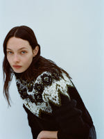 Image of model wearing Lizzy Sweater in Textured Fairisle in Black multi against a light blue background