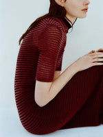 Image of model wearing Meline Dress in Cashmere Silk Stripe in Claret, black on a light blue background