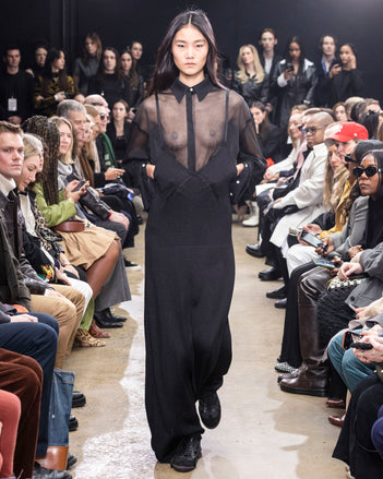 Model Walking In Proenza Schouler Fall Winter 2024 Runway Show Wearing Smithson Shirt In Black Silk Knit, Bella Dress In Black Lacquered Knit, And Track Sneakers In Black Nappa/nylon/suede