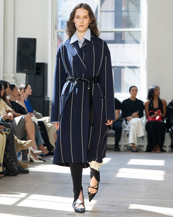 Image of model walking Proenza Schouler SS25 Runway wearing Marina Coat in Stripe Bi-Stretch Viscose in Navy Multi and Hunter Top in Stripe Cotton Silk Shirting in Pale Blue Multi and Zip Legging in Technical Jersey in Black and Slash Slingback Pump in BLACK