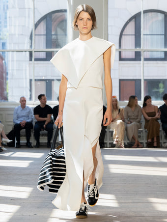 Image of model walking Proenza Schouler SS25 Runway wearing Selene Dress in Bi-Stretch Viscose in Off White and Tate Bag in Black Smooth Calf in BLACK and Track Sneaker in BLACK/WHITE