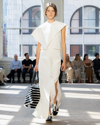 Image of model walking Proenza Schouler SS25 Runway wearing Selene Dress in Bi-Stretch Viscose in Off White and Tate Bag in Black Smooth Calf in BLACK and Track Sneaker in BLACK/WHITE