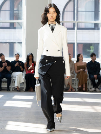 Image of model walking Proenza Schouler SS25 Runway wearing Marine Jacket in Bi-Stretch Viscose in Off White and Prescott Top in Matte Viscose Crepe in White Multi and Oliver Pant in Wool Gabardine in Black and Silo Bag in Smoke Satin in SMOKE and Slash Slingback Pump in SILVER SPECCHIO