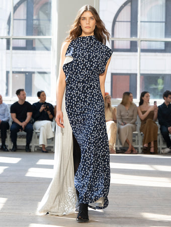 Image of model walking Proenza Schouler SS25 Runway wearing Devyn Dress in Printed Silk Viscose in Navy Multi and Slash Tie Sandal in BLACK