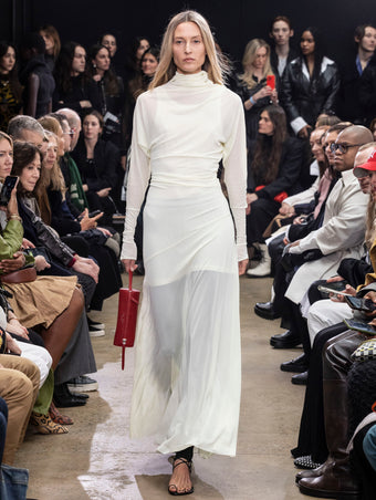 Model Walking in Proenza Schouler Fall Winter 2024 Runway Show Wearing Paula Dress in Citron Sheer Crepe Jersey, Stiltsman Stirrup in Black Compact Jersey, Silo Bag in Rosewood Nappa, and Tee Toe Ring Sandal in Black Nappa