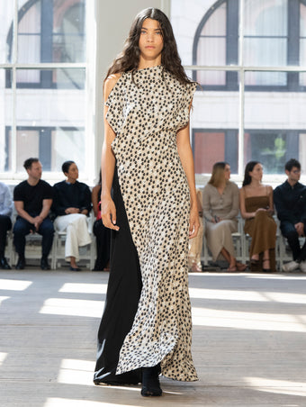 Image of model walking Proenza Schouler SS25 Runway wearing Devyn Dress in Printed Silk Viscose in Sand Multi and Slash Tie Sandal in BLACK