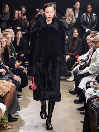 Model Walking in Proenza Schouler Fall Winter 2024 Runway Show Wearing Fiona Coat in Black Sheared Toscana, Silo Bag in Rosewood Nappa, and Park Loafers in Black Slick Nappa