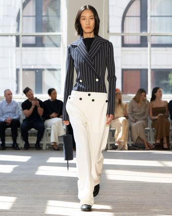 Image of model walking Proenza Schouler SS25 Runway wearing Marine Jacket in Bi-Stretch Viscose in Navy Multi and Prescott Top in Matte Viscose Crepe in Black and Oliver Pant in Wool Gabardine in Off White and Silo Bag in Deep Navy Kid Suede in DEEP NAVY and Mini Monogram Loafer in BLACK