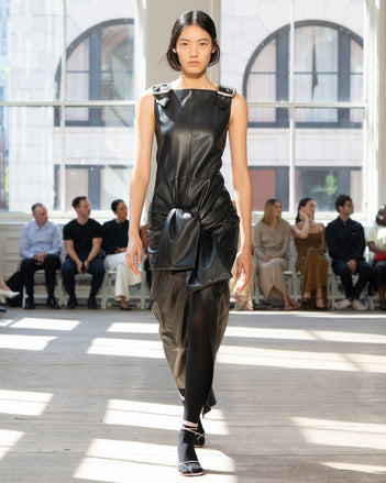 Image of model walking Proenza Schouler SS25 Runway wearing Jackie Dress in Nappa in Black and Slash Tie Sandal in LILAC