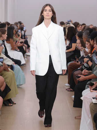 Weyes blood walking Proenza Schouler SS24 Runway in Talia T-shirt In White Eco Cotton Jersey, Otis Pant In Black Viscose Wool Suiting, Sandis Jacket In White Cotton Viscose Suiting, Flip Shoulder Bag In Black Nappa Leather, Tee Toe Ring Sandals In Black + Cream Nappa Lux