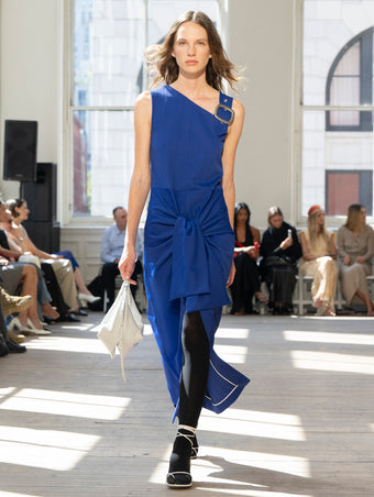 Image of model walking Proenza Schouler SS25 Runway wearing Jackie Dress in Technical Nylon Jacquard in Cobalt and Tetra Shoulder Bag in Smoke Nappa in SMOKE and Slash Tie Sandal in WHITE