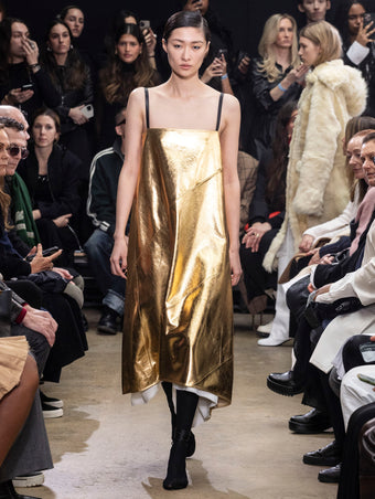 Model Walking in Proenza Schouler Fall Winter 2024 Runway Show Wearing Ivonne Dress in Gold Polished Nappa and Tee Over the Knee Boots in Black Viscose Knit