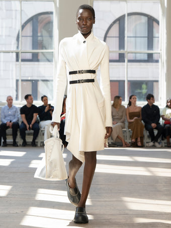 Image of model walking Proenza Schouler SS25 Runway wearing Reinhardt Dress in Wool Cashmere Knit in White and Days Carryall in Off-White Mesh in OFF-WHITE and Box Bag in Black Croc Embossed Calf in BLACK and Silo Bag in Light Gold Soft Mirrored Fabric in LIGHT GOLD and Caribou Mule in Chalk