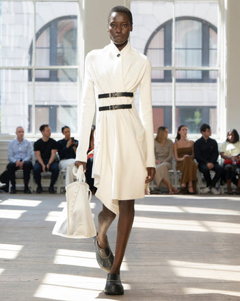 Image of model walking Proenza Schouler SS25 Runway wearing Reinhardt Dress in Wool Cashmere Knit in White and Days Carryall in Off-White Mesh in OFF-WHITE and Box Bag in Black Croc Embossed Calf in BLACK and Silo Bag in Light Gold Soft Mirrored Fabric in LIGHT GOLD and Caribou Mule in Chalk