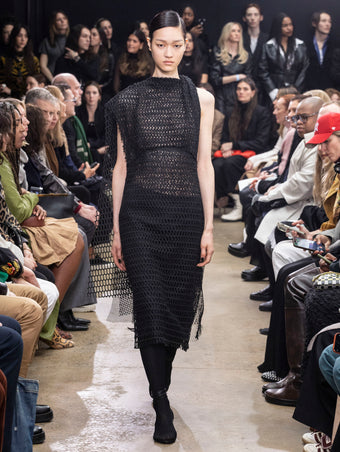 Model Walking in Proenza Schouler Fall Winter 2024 Runway Show Wearing Maude Dress in Black Technical Lace and Tee Over the Knee Boots in Black Viscose Knit